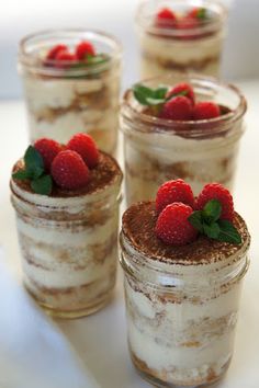 four jars filled with desserts and topped with strawberries on the top one has chocolate cake, while the other has raspberries