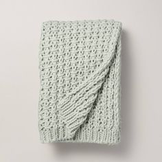 a green knitted blanket laying on top of a white wall