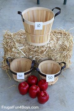 three buckets with numbers on them sitting next to straw bales and tomatoes in the middle