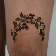 a woman's thigh with black leaves and berries on it