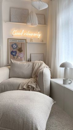 a white couch sitting under a neon sign in a living room next to a window