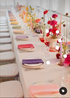 a long table is set with place settings and flowers in vases on the tables