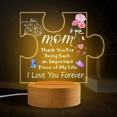 a light up puzzle piece with the words mom and flowers on it, sitting next to a