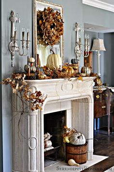 a fireplace decorated for fall with pumpkins, gourds and other autumn decorations