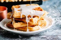 a stack of waffles with icing drizzled over them on a plate