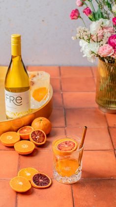 an orange cut in half next to a bottle of wine and some sliced grapefruits