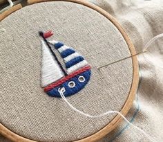 a close up of a small sailboat on a piece of fabric in a hoop