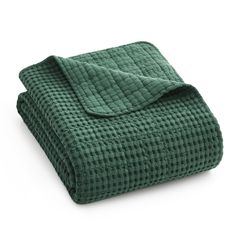 a green blanket folded on top of a white surface with the cover pulled down to reveal a quilted pattern