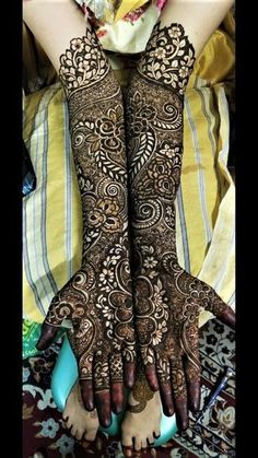 two hands with henna tattoos on them, one is showing off the intricate design