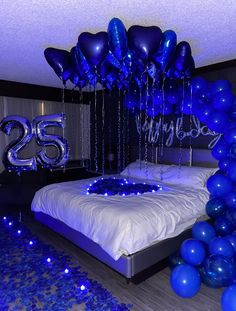 a bed with blue balloons on it and the number twenty five in front of it