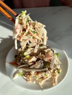 chopsticks holding up food on a white plate