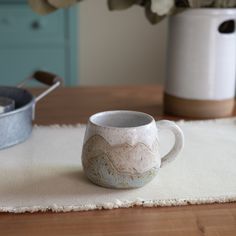 Handcrafted and carved snowy mountain mug here to add a bit of unique handmade cheer to your morning coffee routine! HOW IT'S MADE: Each mug is individually crafted on the potter's wheel using speckled clay. A handle is extruded and carefully attached. Unique mountain outlines are then carved and shaped onto each mug. Because of this, every mountain mug is one-of-a-kind, though each will bear a strong resemblance to those in the photos.  STYLE NAME: Snowy Mountain Mug INCLUDES: 1 12oz or 16oz Snowy Mountain Mug APPROXIMATELY MEASURES:  LARGE 16oz BARREL MUG: 3 1/2" Tall 3" Wide | 16oz, 500ml, Grande SMALL 12oz BARREL MUG: 3" Tall x 3" Wide | 12oz, 350ml, Tall HANDMADE IN LOS OSOS, CALIFORNIA DURABLE AMERICAN STONEWARE POTTERY FOOD, OVEN, MICROWAVE & DISHWASHER SAFE LEAD & CADMIUM FREE POTT Ceramic Mountain Mug, Mountain Mugs, Mountain Mug, Nature Mug, Tea Kitchen, Speckled Clay, Snowy Mountain, Mug Handmade, Coffee Routine