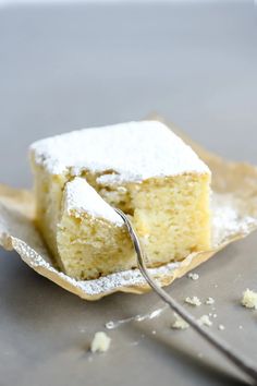 a piece of cake with powdered sugar on top and a fork in the middle