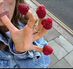 a woman with four raspberries on her fingers in the shape of a hand