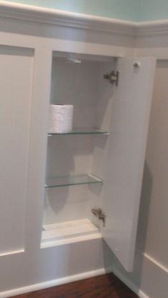 an empty bathroom with shelves and toilet paper