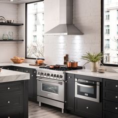 a kitchen with black cabinets and white counter tops, an island in the middle is surrounded by pots and pans