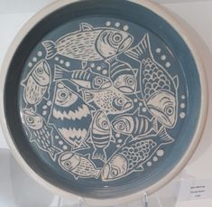 a blue and white plate with fish on it sitting on a shelf next to other items