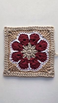 a crocheted square with a red flower on it