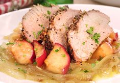 two slices of pork with apples and onions on a bed of noodles, garnished with parsley