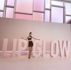 a woman standing in front of the words lipglow