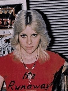 a woman with blonde hair wearing a red t - shirt sitting in front of a radio