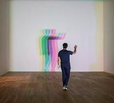 a man standing in an empty room with his hand up