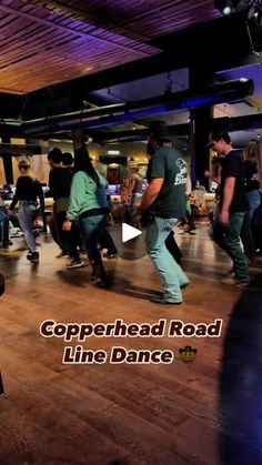 a group of people are dancing in a room with wooden floors and purple lighting on the ceiling