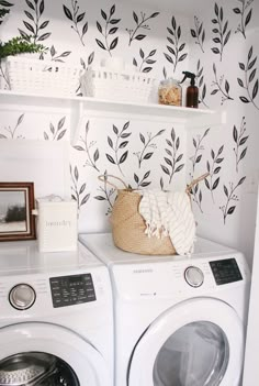 a washer and dryer sitting next to each other in front of a wall with leaves on it