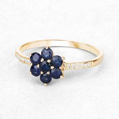 a gold ring with blue sapphires and diamonds on the side, sitting on a white surface