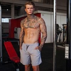 a man with tattoos standing in front of a gym machine