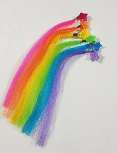 there are three rainbow colored hair clips on the white surface, and one is holding a star