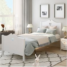 a white bed sitting in a bedroom on top of a wooden floor next to a window