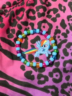 a pony beaded bracelet sitting on top of a pink and black animal print blanket