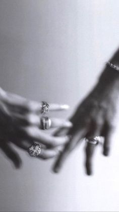 two hands reaching out towards each other with rings on their fingers and diamond bracelets