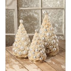 two small white christmas trees sitting on top of a wooden table