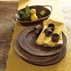 the table is set with yellow linens and wicker dishes