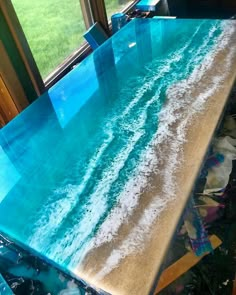 a table that has been painted with blue and white paint on it, in front of a window