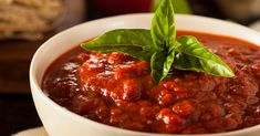 a white bowl filled with tomato sauce and basil