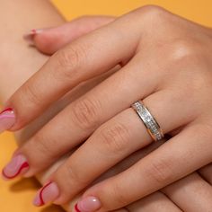 a woman's hand with pink and white manicured nails holding a wedding ring