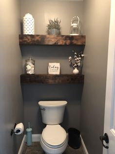 a white toilet sitting in a bathroom next to a wooden shelf