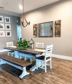 a dining room table with two benches in front of it and pictures on the wall