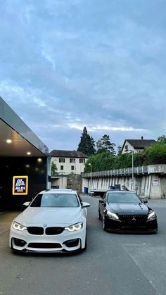 two bmws parked in front of a building with an awning on the roof