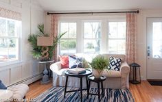 a living room filled with furniture and a blue rug on top of a hard wood floor