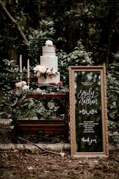 a wedding cake sitting on top of a table next to a sign