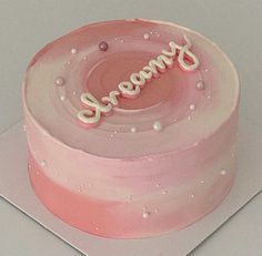 a pink and white cake with the word dream on it's frosted icing