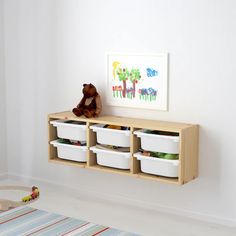 a teddy bear sitting on top of a wooden shelf filled with containers and bins