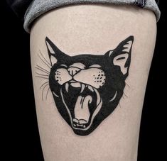 a black and white cat tattoo on the right side of the leg, with its mouth open