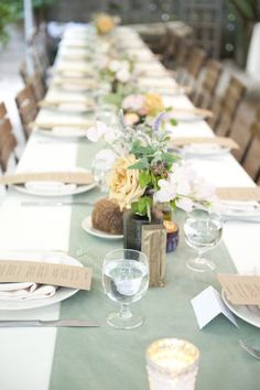 a long table set with place settings and flowers