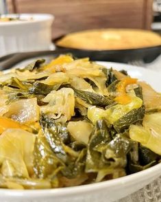 a white bowl filled with green vegetables on top of a table next to other dishes