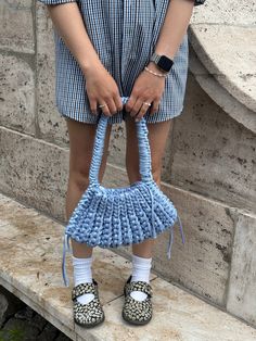 a woman holding a blue purse on top of a stone step